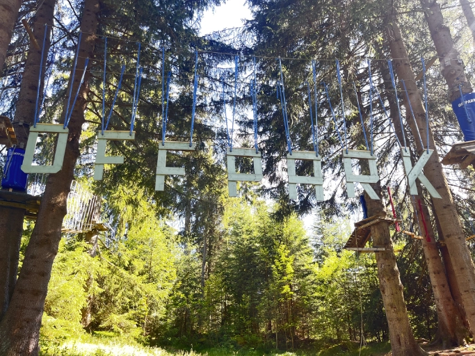 Offpark Prášily – dřevěný nápis lanového parku mezi stromy