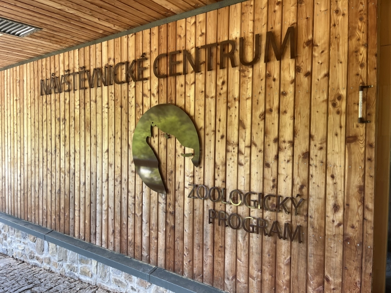 Fasáda Návštěvnického centra Srní s logem vyjícího vlka a nápisem Zoologický program